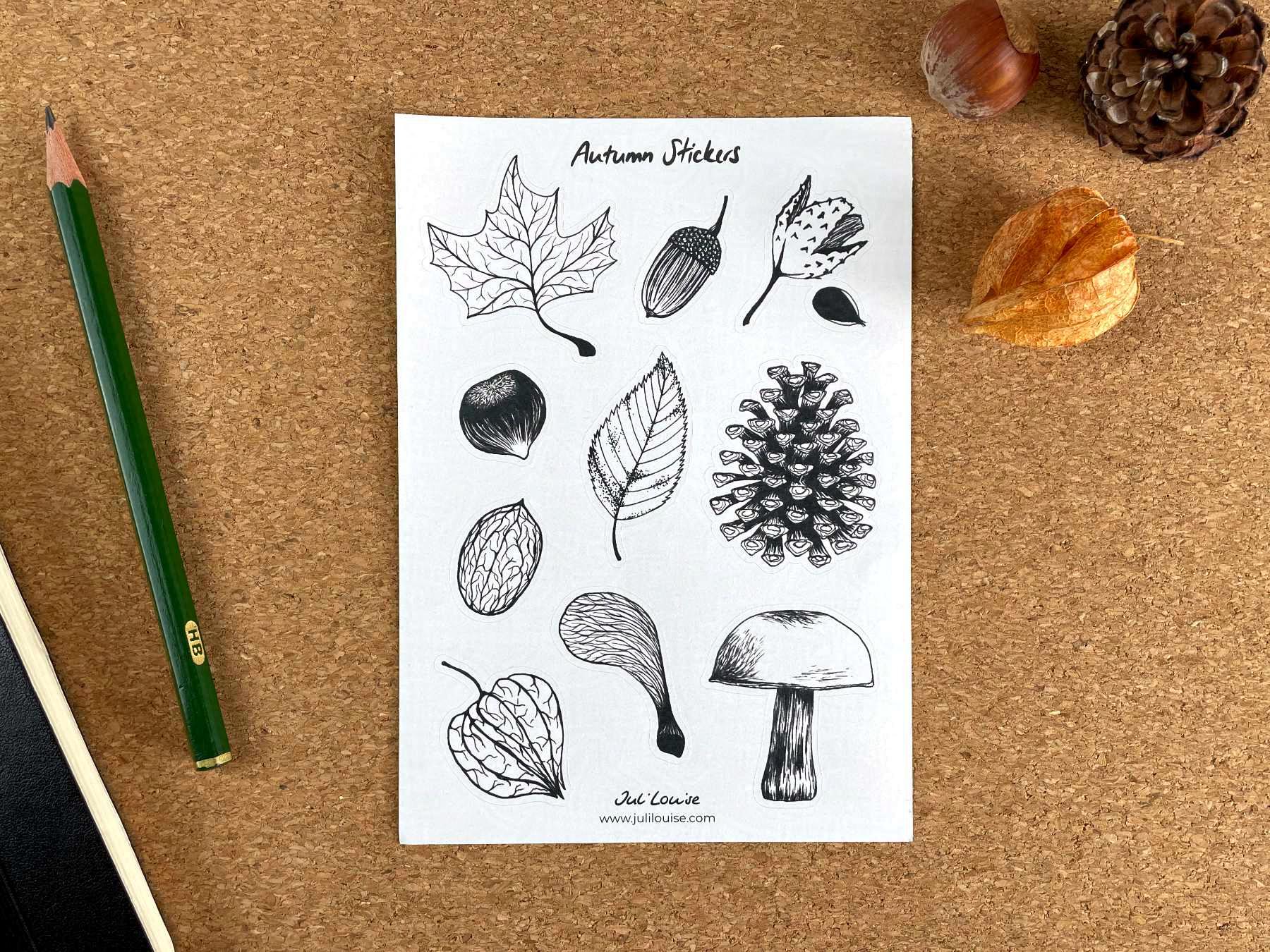 Ein Stickerbogen aus weißem Aufkleberpapier auf einem Tisch. Die Sticker zeigen jeweils eine Zeichnung eines Herbst-Motivs.