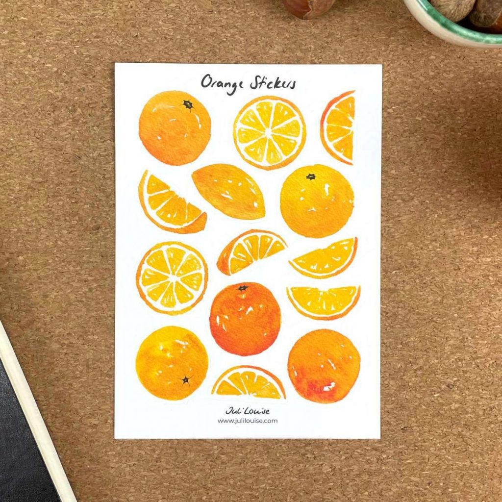 Ein Stickerbogen liegt auf einem Tisch. Der Stickerbogen enthält Aufkleber, die mit Aquarellfarben gemalte Orangen in verschiedenen Ansichten zeigen.